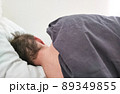 Man sleeping in bed under blanket in the morning.  89349855