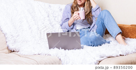 Cropped happy woman girl with wavy light hair working office from home sitting on bed. Using computer video chat and drinking coffee. Distance learning online education and work. Banner space for text Cropped happy woman girl with wavy light hair working office from home sitting on bed. Using computer video chat and drinking coffee. Distance learning online education and work. Banner space for text 89350200