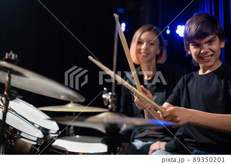 Young woman teaching boy to play drums. Young woman teaching boy to play drums. 89350201