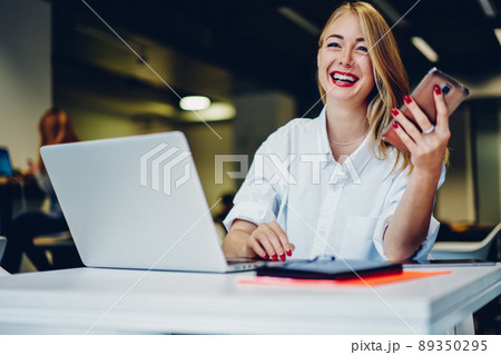 Woman working remotely on laptop and messaging on phone 89350295