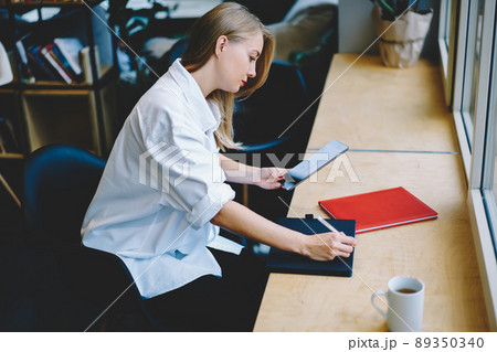 Concentrated woman writing in notebook Concentrated woman writing in notebook 89350340