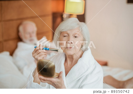 A gray-haired woman doing make up in the morning A gray-haired woman doing make up in the morning 89350742