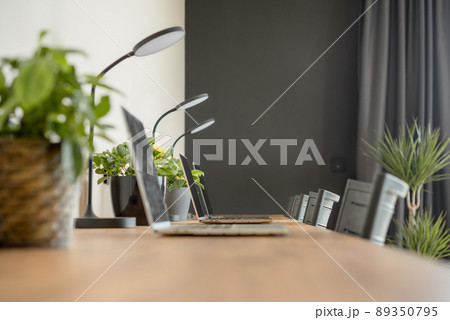 Wooden desktop with laptops in a modern interior of a cozy coworking space. 89350795