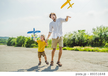 Happy father and son playing with toy airplane against old runway background. Traveling with kids concept 89351648