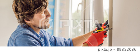 Man in a blue shirt does window installation BANNER, LONG FORMAT 89352036