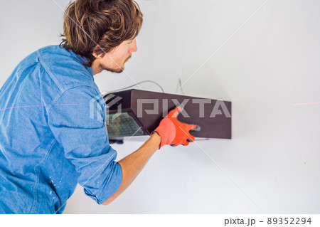 A man is installing an electrical device on a wall in a new apartment A man is installing an electrical device on a wall in a new apartment 89352294