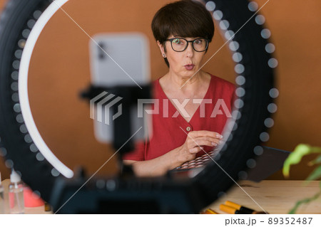 Beauty and cosmetics e-commerce and blogging concept - professional mature female make up artist testing new cosmetics recording video review on cosmetic products at home 89352487