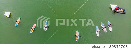 Strong men floating on a SUP boards in a beautiful bay on a sunny day. Aerial view of the men crosses the bay using the paddleboard. Water sports, competitions BANNER, LONG FORMAT Strong men floating on a SUP boards in a beautiful bay on a sunny day. Aerial view of the men crosses the bay using the paddleboard. Water sports, competitions BANNER, LONG FORMAT 89352703