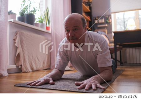 Senior man doing yoga pose or pilates at home. Senior man doing yoga pose or pilates at home. 89353176