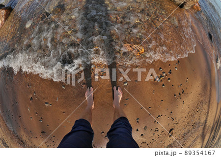 First Person Fisheye Perspective of Man's Feet in Shallow Water with Waves Rolling into Sandy Beach First Person Fisheye Perspective of Man's Feet in Shallow Water with Waves Rolling into Sandy Beach 89354167