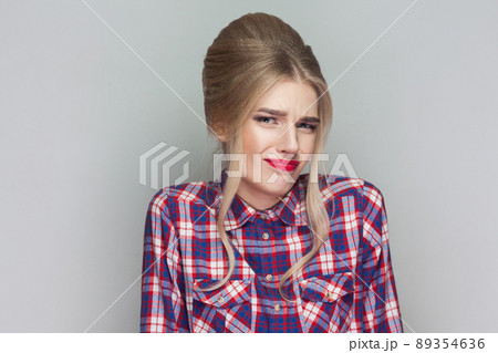 I dont know. confused beautiful girl with pink checkered shirt, collected updo hairstyle and makeup standing and looking away with doubtful face. indoor studio shot, isolated on gray background. I dont know. confused beautiful girl with pink checkered shirt, collected updo hairstyle and makeup standing and looking away with doubtful face. indoor studio shot, isolated on gray background. 89354636