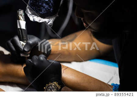 Tattoo artist is concentrated on his work. Closeup. Tattoo artist is concentrated on his work. Closeup. 89355421