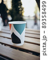 Paper cup with tea coffee drink on a wooden table against the background plant and a green wall. Zero West Concept. 89358499