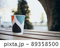 Paper cup with tea coffee drink on a wooden table against the background plant and a green wall. Zero West Concept. 89358500