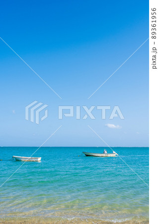 晴れの沖縄の青い空と白い砂浜と青い海に船が浮かぶ/新原ビーチにて撮影 2022年4月 晴れの沖縄の青い空と白い砂浜と青い海に船が浮かぶ/新原ビーチにて撮影 2022年4月 89361956