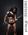 Female fitness model posing with dumbbells on black background 89362063