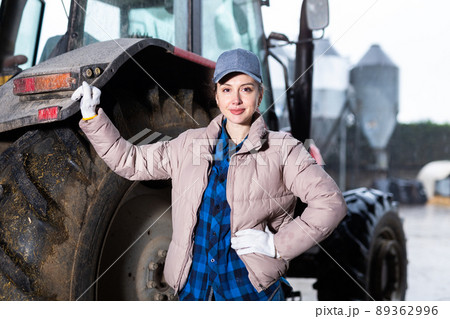 Successful female farmer posing near farming equipment in backyard Successful female farmer posing near farming equipment in backyard 89362996