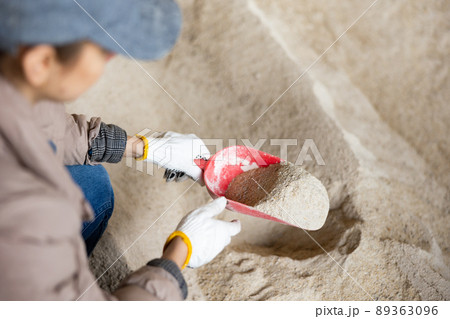 Female farmer scooping up maize meal from pile with scoop Female farmer scooping up maize meal from pile with scoop 89363096