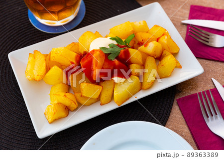 Spanish dish Patatas bravas with hot sauce 89363389