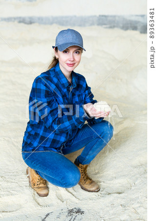 Young woman livestock breeder checking quality of soybean meal in farm storage Young woman livestock breeder checking quality of soybean meal in farm storage 89363481