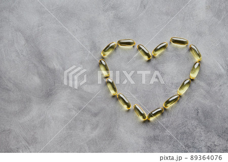 Heart-shaped omega-3 capsules on a gray background. The concept of medicine and healthy living. Top view. Heart-shaped omega-3 capsules on a gray background. The concept of medicine and healthy living. Top view. 89364076