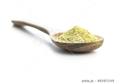 Ground green coffee in wooden spoon. Unroasted coffee isolated on white background. 89365549