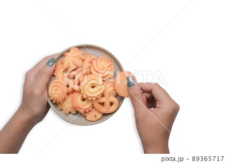 Woman hand holding plate with  homemade Danish butter cookies isolated on white background. 89365717