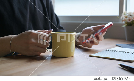 Stylish man hand holding coffee cup and using mobile phone on wooden table. Stylish man hand holding coffee cup and using mobile phone on wooden table. 89365922