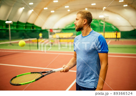 Instructor or coach teaching how to play tennis on a court indoor Instructor or coach teaching how to play tennis on a court indoor 89366524