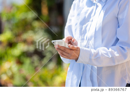 屋外でスマートフォンを触るミドル女性 89366767