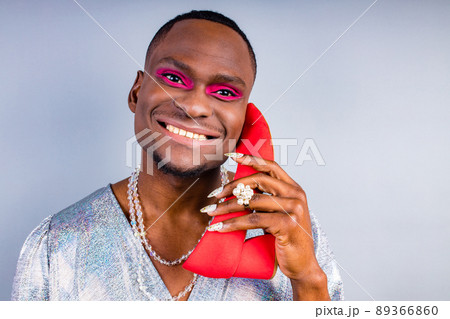 african american cross dressing trans drag queen holding a red shoe in studio white wall 89366860