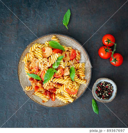 fusilli pasta with tomato sauce, chicken fillet with basil leaves 89367697