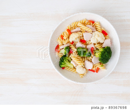 Pasta fusilli with vegetables, boiled steamed meat, white sauce on white wooden table Pasta fusilli with vegetables, boiled steamed meat, white sauce on white wooden table 89367698