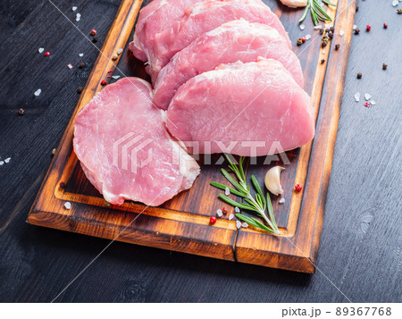 Pork steak, raw carbonate fillet on dark background, meat with rosemary, seasonings, side view Pork steak, raw carbonate fillet on dark background, meat with rosemary, seasonings, side view 89367768