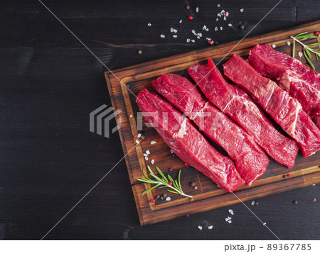 Raw meat, beef steak with seasoning on chopping board on dark background with rosemary, 89367785