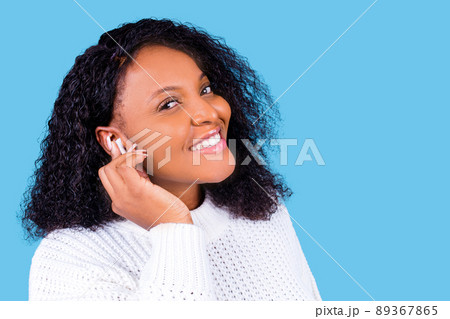 african american woman isolated on blue background in studio Listen music with earpods african american woman isolated on blue background in studio Listen music with earpods 89367865