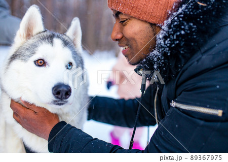 mixed race man hug his dog husky in winter forest park close up 89367975