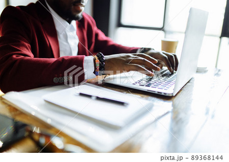 Smiling businessman in a marsala jacket working on laptop computer in office 89368144