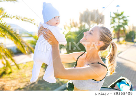 happy blonde woman kissind and feelinf adore to her stroll new born kid in tropics beach park outdoors happy blonde woman kissind and feelinf adore to her stroll new born kid in tropics beach park outdoors 89368409