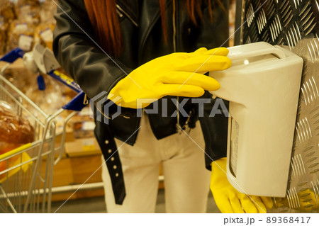 redhaired ginger woman in casual black leather jacket , rubber gloves yellow use antibacterial gel in empty super market second wave redhaired ginger woman in casual black leather jacket , rubber gloves yellow use antibacterial gel in empty super market second wave 89368417