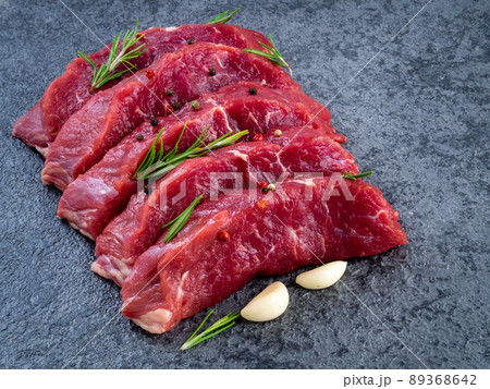 Raw meat, beef steak with seasoning on a black stone table, side view Raw meat, beef steak with seasoning on a black stone table, side view 89368642