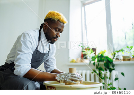 mixed race man making a vase in pottery studio 89369110