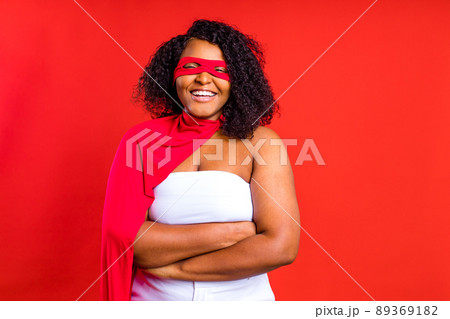 spanish woman in eye mask and superhero cloak in red studio background 89369182