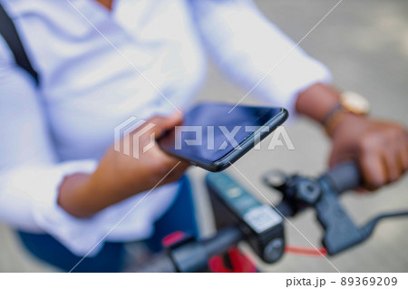 afro american woman activate and prepay a rental e-scooter or an e-bicycle on the street afro american woman activate and prepay a rental e-scooter or an e-bicycle on the street 89369209