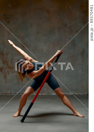 beautiful girl in sports uniform is training kung fu in the studio, fighter athlete, practicing martial arts with a stick 89370481