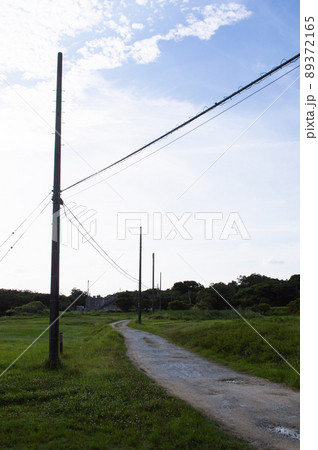 両側が草原の未舗装路の道沿いに電柱が立ち並んでいる 両側が草原の未舗装路の道沿いに電柱が立ち並んでいる 89372165
