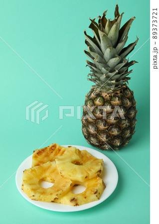 Pineapple and plate with grilled slices on mint background 89373721