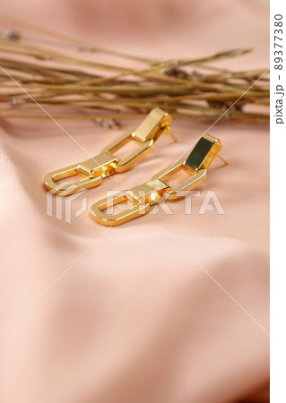 Gold earrings close-up decoration. Luxury female jewelry. Vertical photo 89377380