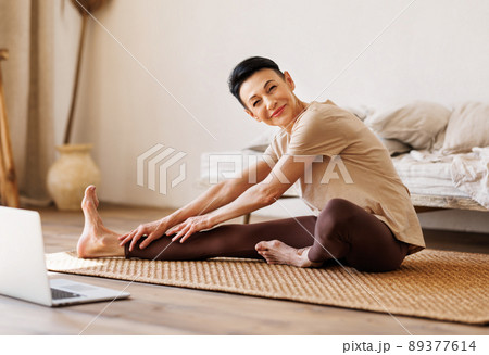 Mature female stretching on floor in morning 89377614