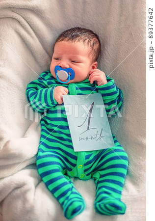 Cute baby with 1 month old milestone card in his hand 89377642